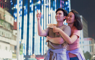 Young couple enjoying a romantic night stroll in bustling Hanoi, Vietnam under vibrant city lights