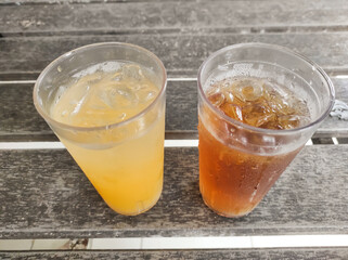 A glass of iced orange and iced tea on a wooden table. A refreshing drink to quench your thirst and accompany spicy food in a restaurant. Drink or beverages photography with negative space