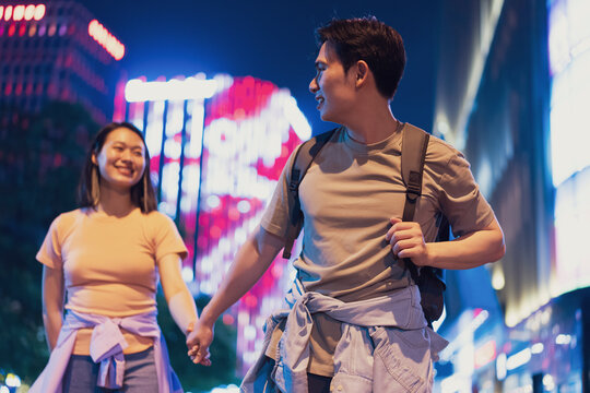 Couple exploring vibrant nightlife in Hanoi, Vietnam, holding hands and enjoying the city lights together - Powered by Adobe