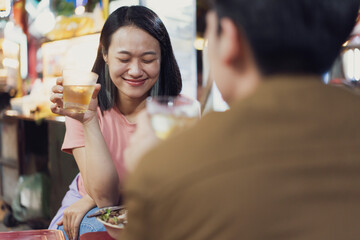 Friends enjoying drinks and local food at a vibrant night market in Hanoi, Vietnam