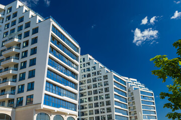 City view on a sunny day. Modern building and houses against the blue sky.