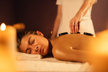 Woman getting exotic spa massage with hot stones -  Spa treatment, body relaxation life style concept