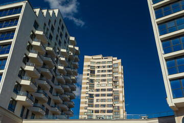 City view on a sunny day. Modern building and houses against the blue sky.