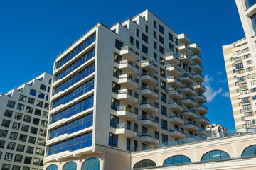 City view on a sunny day. Modern building and houses against the blue sky.