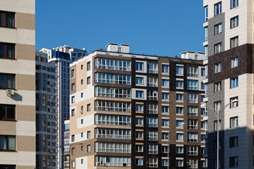 City view on a sunny day. Modern building and houses against the blue sky.