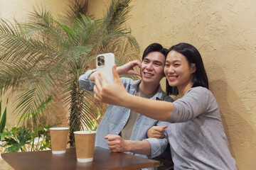 Young Asian couple enjoying time together and taking selfie in cozy cafe in Hanoi, Vietnam at a relaxing afternoon
