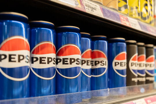 Soft drink cans displayed in a supermarket aisle showcase brand Pepsi