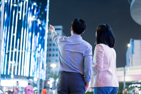 Couple enjoying nightlife in Hanoi, Vietnam while admiring modern architecture and vibrant city lights