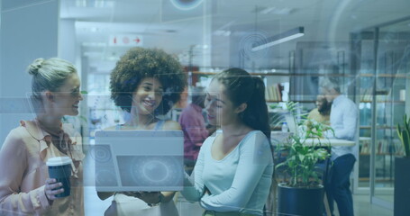 Collaborating trio of women analyzing holographic laptop interface in coworking space, coffee cup