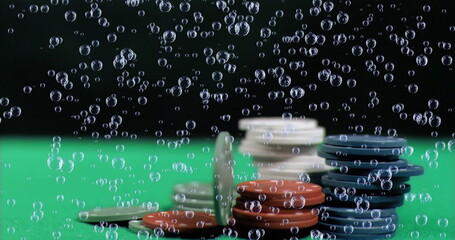 Showing stacks of gaming chips resting on green felt surface, with drifting air bubbles