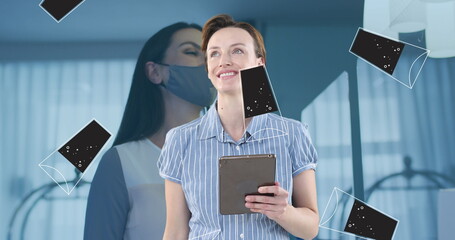 Holding tablet and looking upward in office, showing masked overlay and floating phone icons