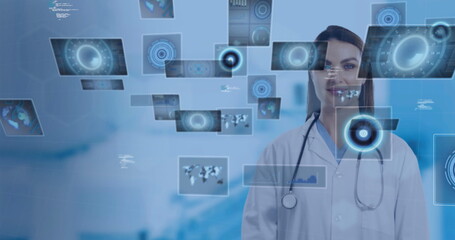 Mid-adult doctor scanning data screens in hospital corridor, with stethoscope, lab coat, copy space