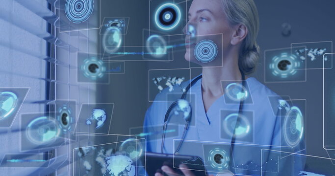 Reviewing tablet data while wearing scrubs and stethoscope at clinic, projecting data panels