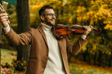 Musician playing viola in autumn forest, enjoying classical music outdoors