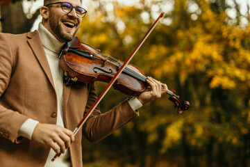 Musician playing violin in autumn park enjoying music and nature