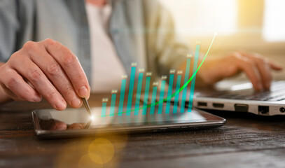 Business professional analyzing data trends on a tablet while working on a laptop during the...