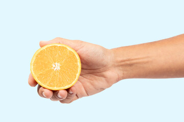 Male hand holding an orange fruit slice isolated on cyan background cutout