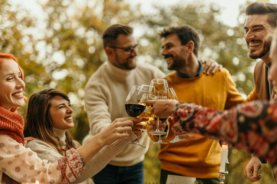 Friends toasting wine glasses, celebrating outdoors in autumn