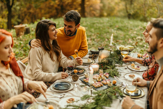 Friends enjoying thanksgiving dinner together outdoors in autumn