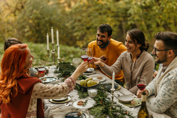 Friends toasting red wine at a festive outdoor dinner party