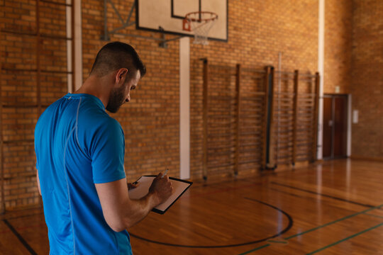 Fototapeta Wooden court is glowing under overhead lights, showing painted floor lines, hoop, and wall bars