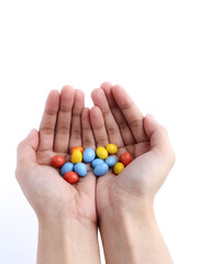 Cupped hands holding colorful candy-coated chocolates on a white background