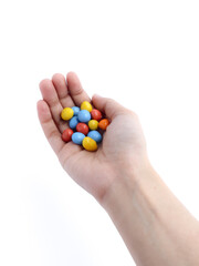 hand holding colorful candy-coated chocolates on a white background