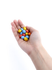 hand holding colorful candy-coated chocolates on a white background
