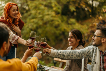 Friends toasting red wine glasses at outdoor autumn party