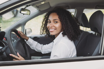 Smiling young woman driving a car. Beautiful student girl behind the wheel, transportation, car...