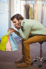 Pastel shopping bags resting on rolling stool in retail showroom, with frosted glass partition