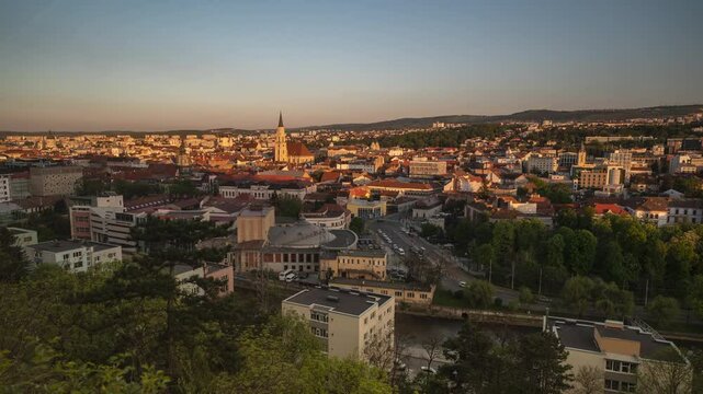 Zoom in timelapse of Cluj Napoca cityscape, at sunset, seen from Cetatuia hill. Sunset shadows descend over the buildings and the very busy street, until it gets dark