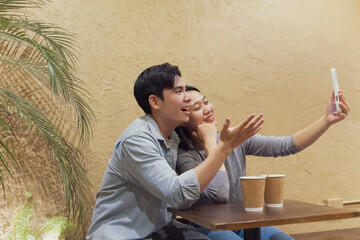 Young Asian couple sharing a joyful moment taking a selfie at a cozy cafe in Hanoi, Vietnam