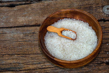 white sugar in wooden bowl, wooden scoop on old wooden background