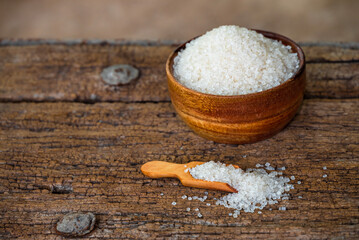 white sugar in wooden bowl, wooden scoop on old wooden background