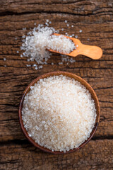 white sugar in wooden bowl, wooden scoop on old wooden background