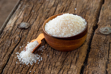 white sugar in wooden bowl, wooden scoop on old wooden background