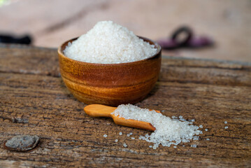 white sugar in wooden bowl, wooden scoop on old wooden background
