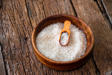 white sugar in wooden bowl, wooden scoop on old wooden background
