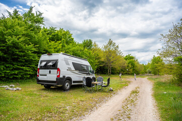 Camper van or motorhome is free camping on the side of the road on Buško lake, Bosnia and Herzegovina. Wild camping in Bosnia, Greece or Croatia in nature next to the lake.