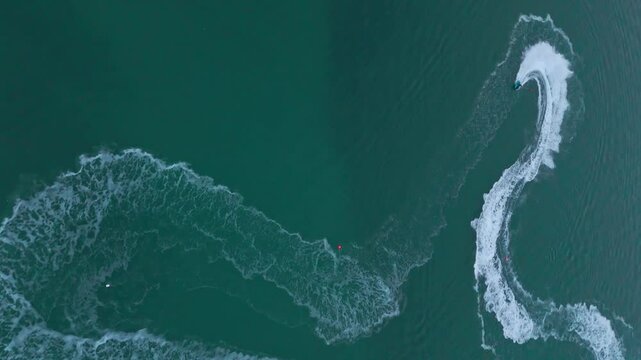 Drone captures jet ski drawing an S-shaped trail across calm sea. Ideal for adventure, water sports, and dynamic cinematic edits.