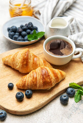 Delicious french croissants with coffee, honey and fresh blueberries for breakfast
