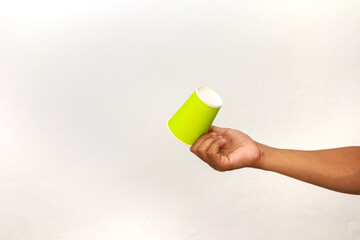 A hand holding a vibrant green disposable cup against a clean white background, creating a...