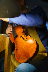 Skilled luthier meticulously crafting viola, assembling delicate instrument parts under bright...