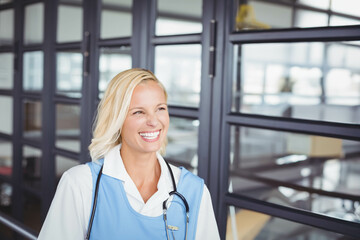 Woman nurse standing in office hallway wearing scrubs with stethoscope copy space
