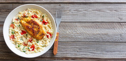 Orzo pasta with fried chicken breast, tomatoes and herbs. Italian food.