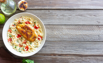 Orzo pasta with fried chicken breast, tomatoes and herbs. Italian food.