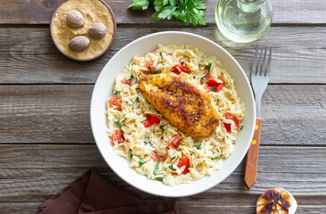 Orzo pasta with fried chicken breast, tomatoes and herbs. Italian food.
