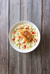 Orzo pasta with fried chicken breast, tomatoes and herbs. Italian food.