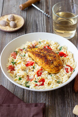 Orzo pasta with fried chicken breast, tomatoes and herbs. Italian food.